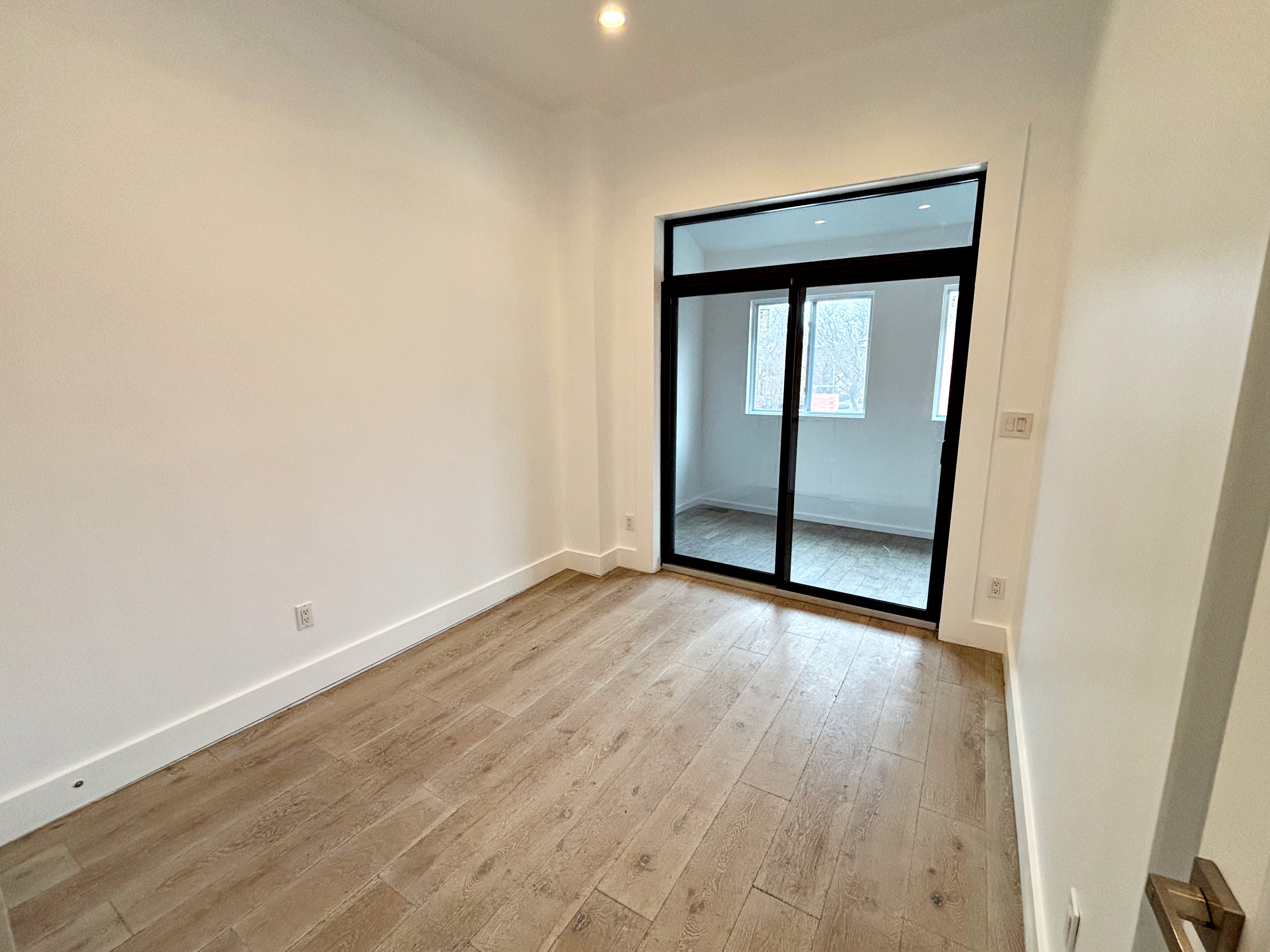 385 Nostrand Avenue, Unit Undisclosed Brooklyn, NY 11216 - Photo 25 of 27 an empty room with wooden floor and sliding door