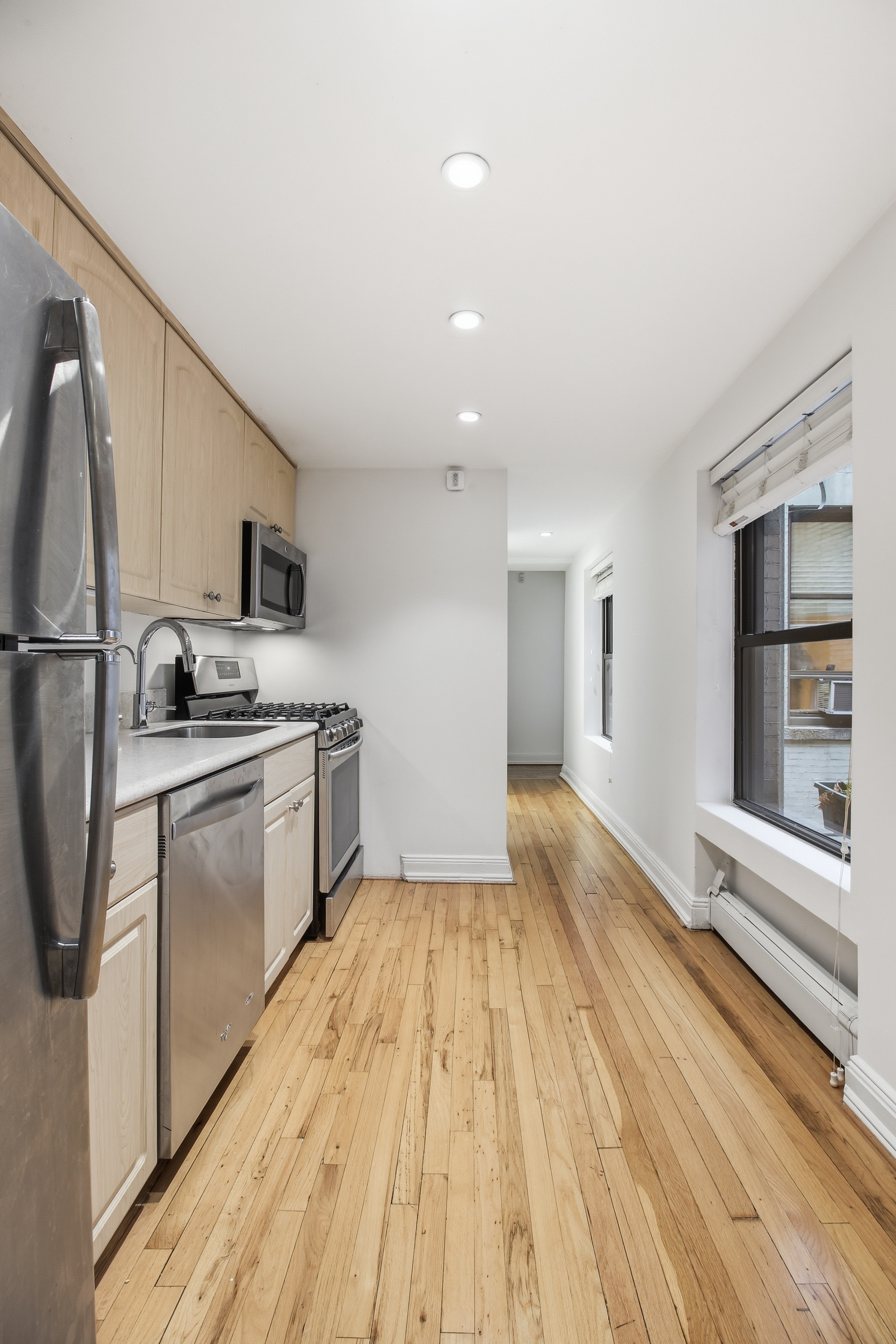 109 East 38th Street, Unit 3A Manhattan, NY 10016 - Photo 5 of 13 a kitchen with white cabinets and stainless steel appliances