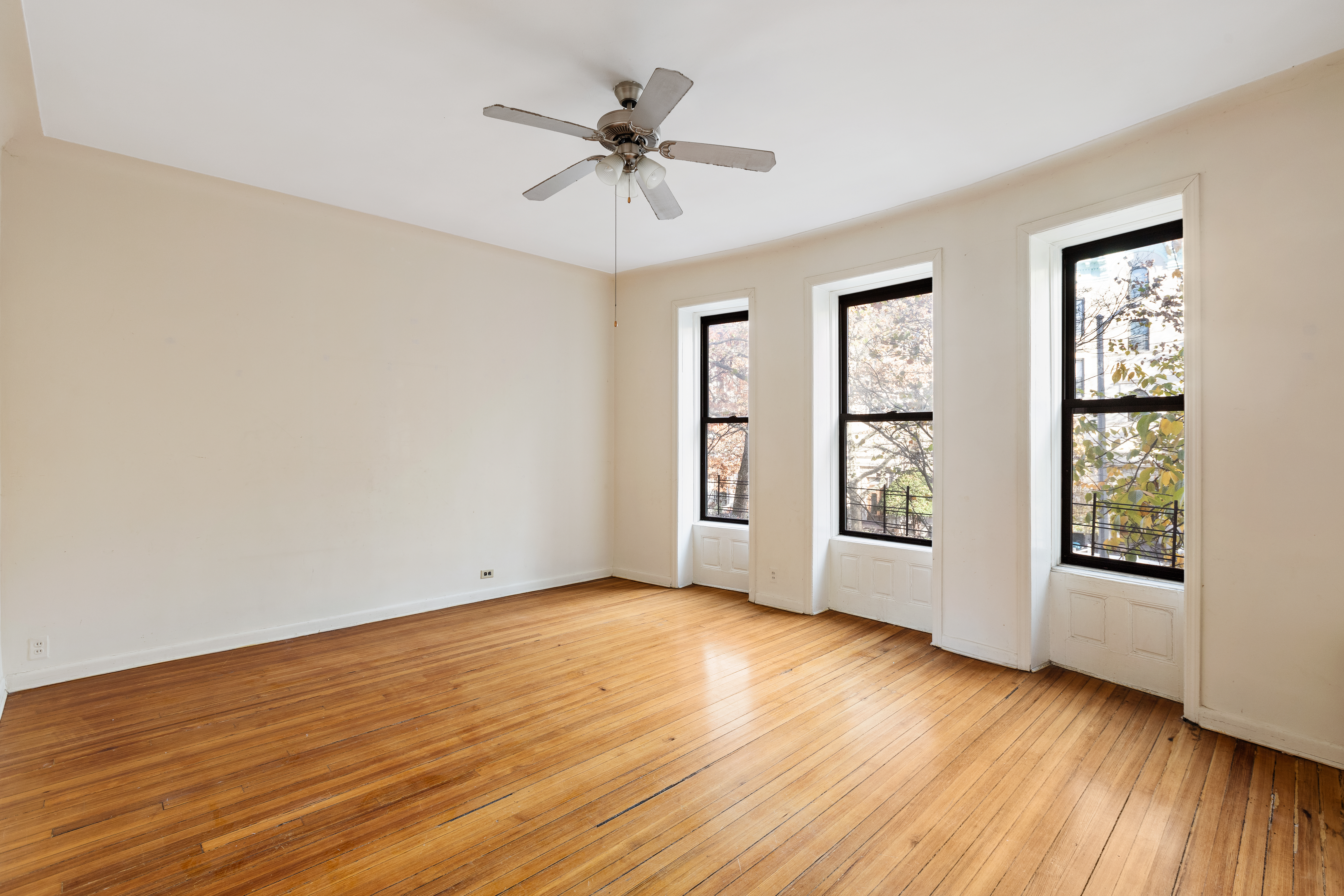 474 3rd Street, Unit 2L Brooklyn, NY 11215 - Photo 3 of 11 an empty room with wooden floor chandelier fan and windows
