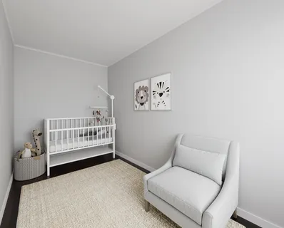 a room with a baby bed a couch and a window