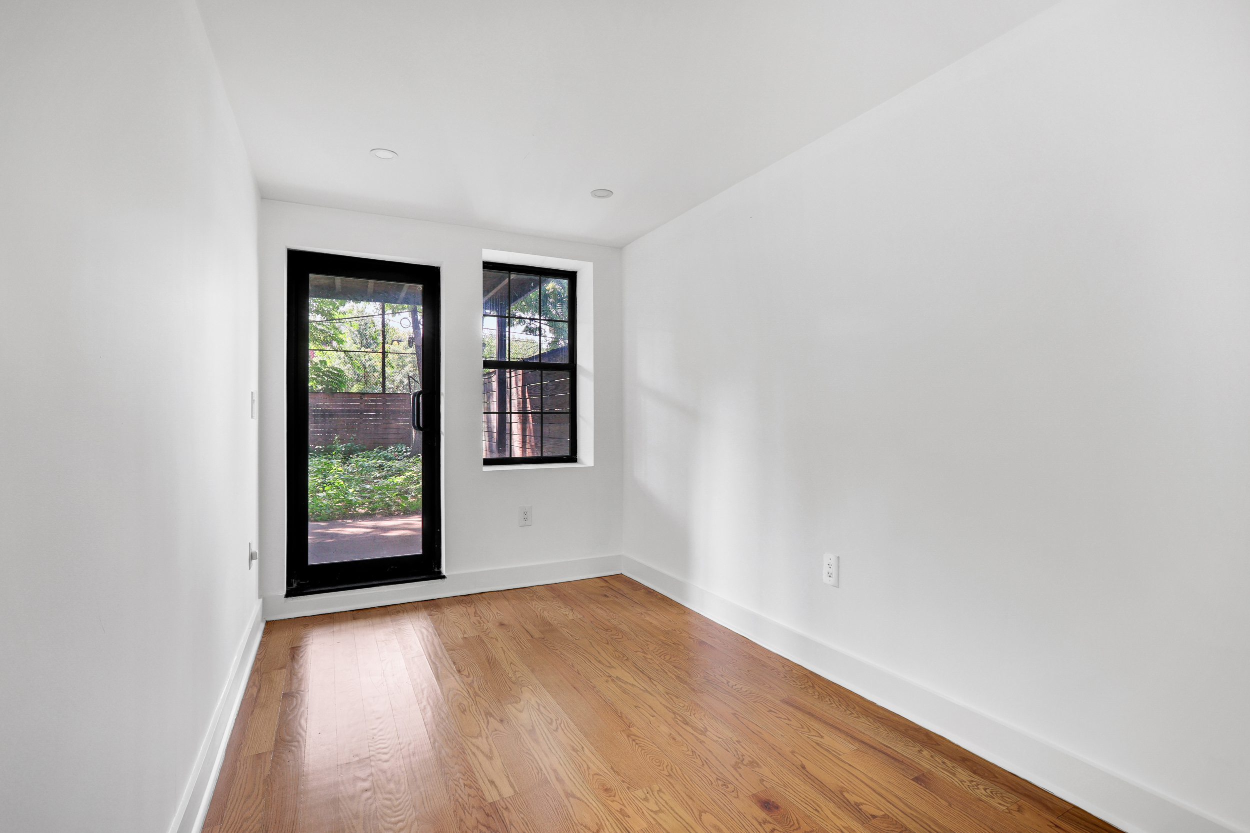 846 Hancock Street, Unit GARDEN Brooklyn, NY 11233 - Photo 4 of 17 an empty room with wooden floor and windows