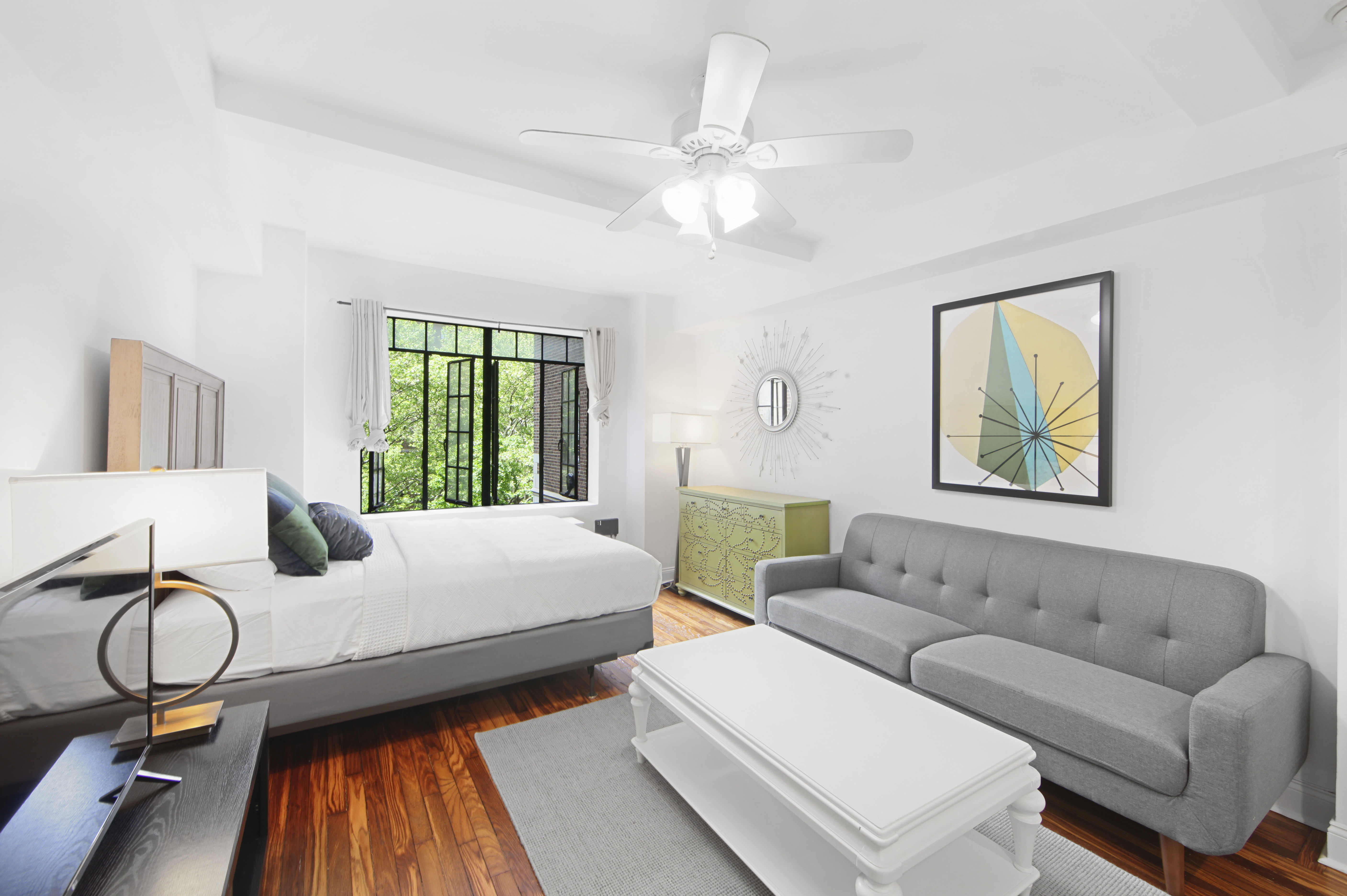 a living room with furniture a chandelier fan and a window