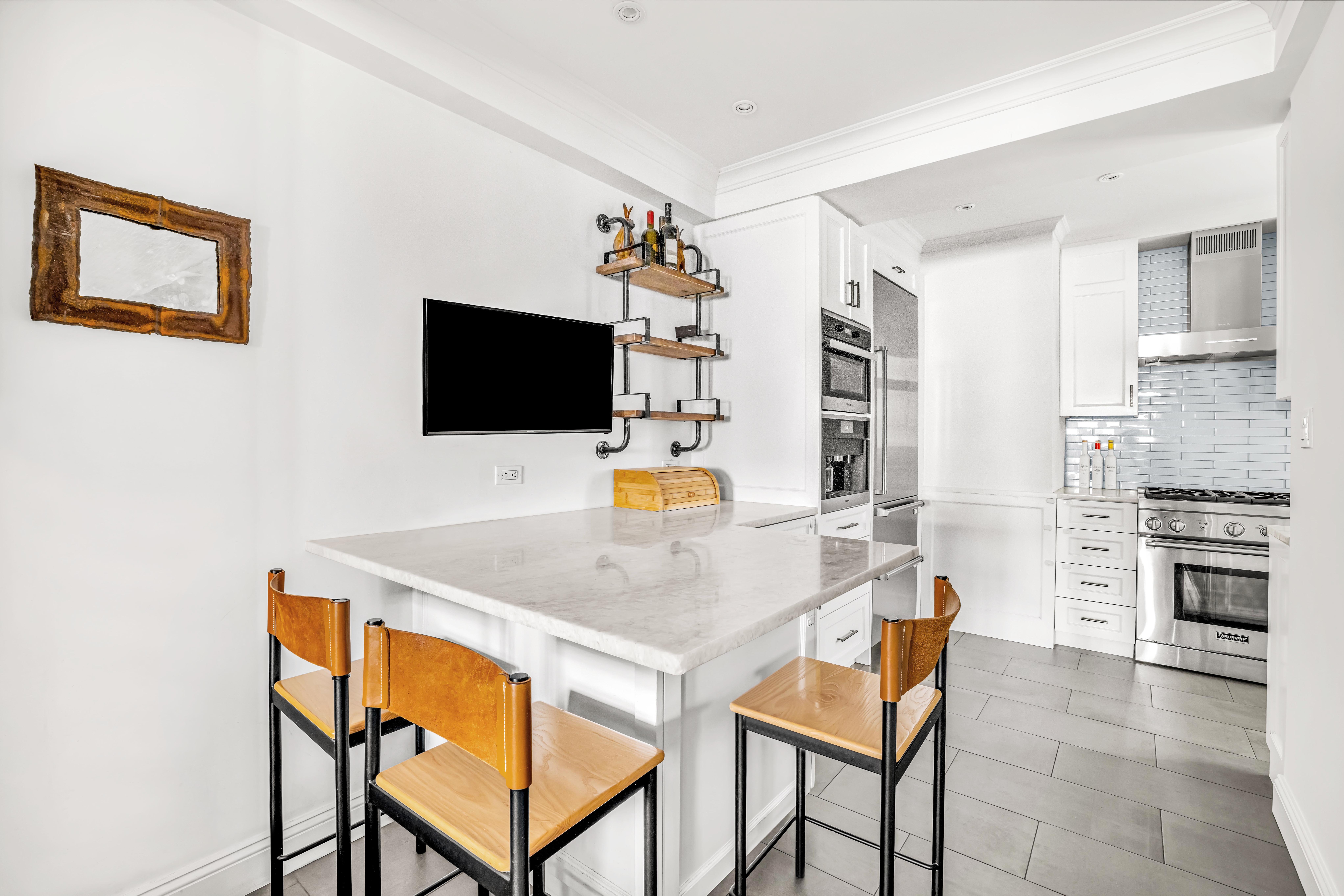 120 East 79th Street, Unit 7BC Manhattan, NY 10075 - Photo 3 of 12 a kitchen with stainless steel appliances a stove a sink a microwave a dining table and chairs with white cabinets