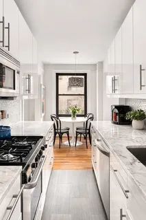 a kitchen with stainless steel appliances a stove a sink a dining table and chairs