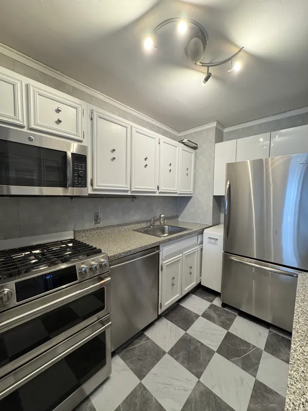 a kitchen with granite countertop stainless steel appliances and white cabinets