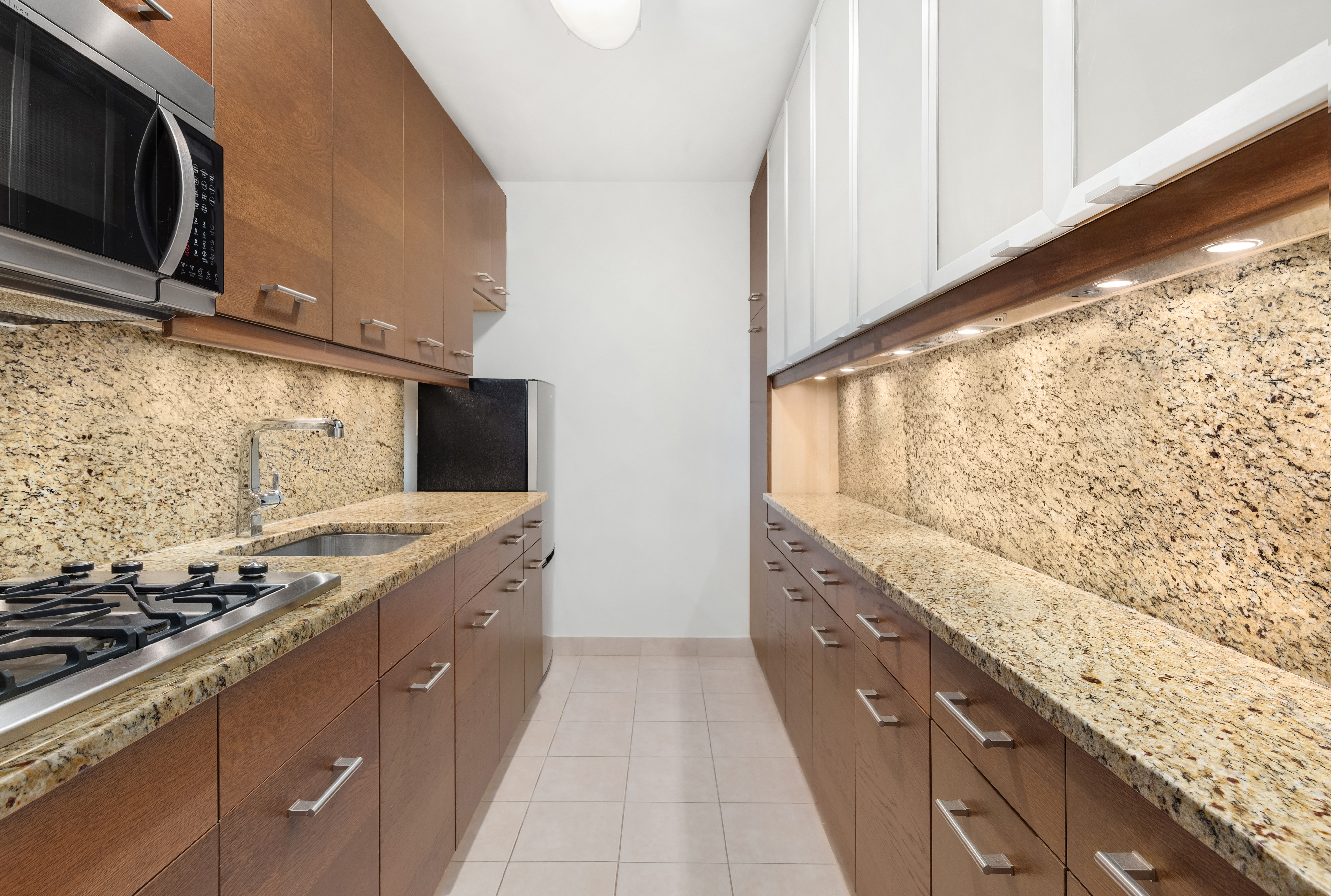 77 West 55th Street, Unit 17F Manhattan, NY 10019 - Photo 3 of 12 a large kitchen with granite countertop a sink and a stove