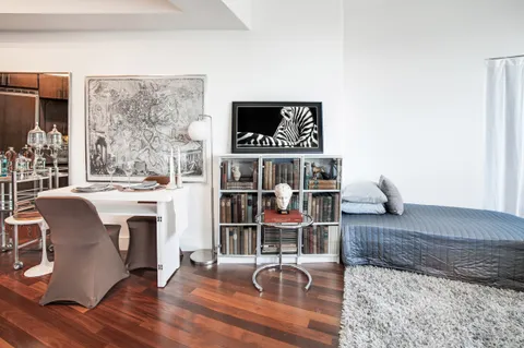a view of a livingroom with furniture wooden floor a flat screen tv and entryway
