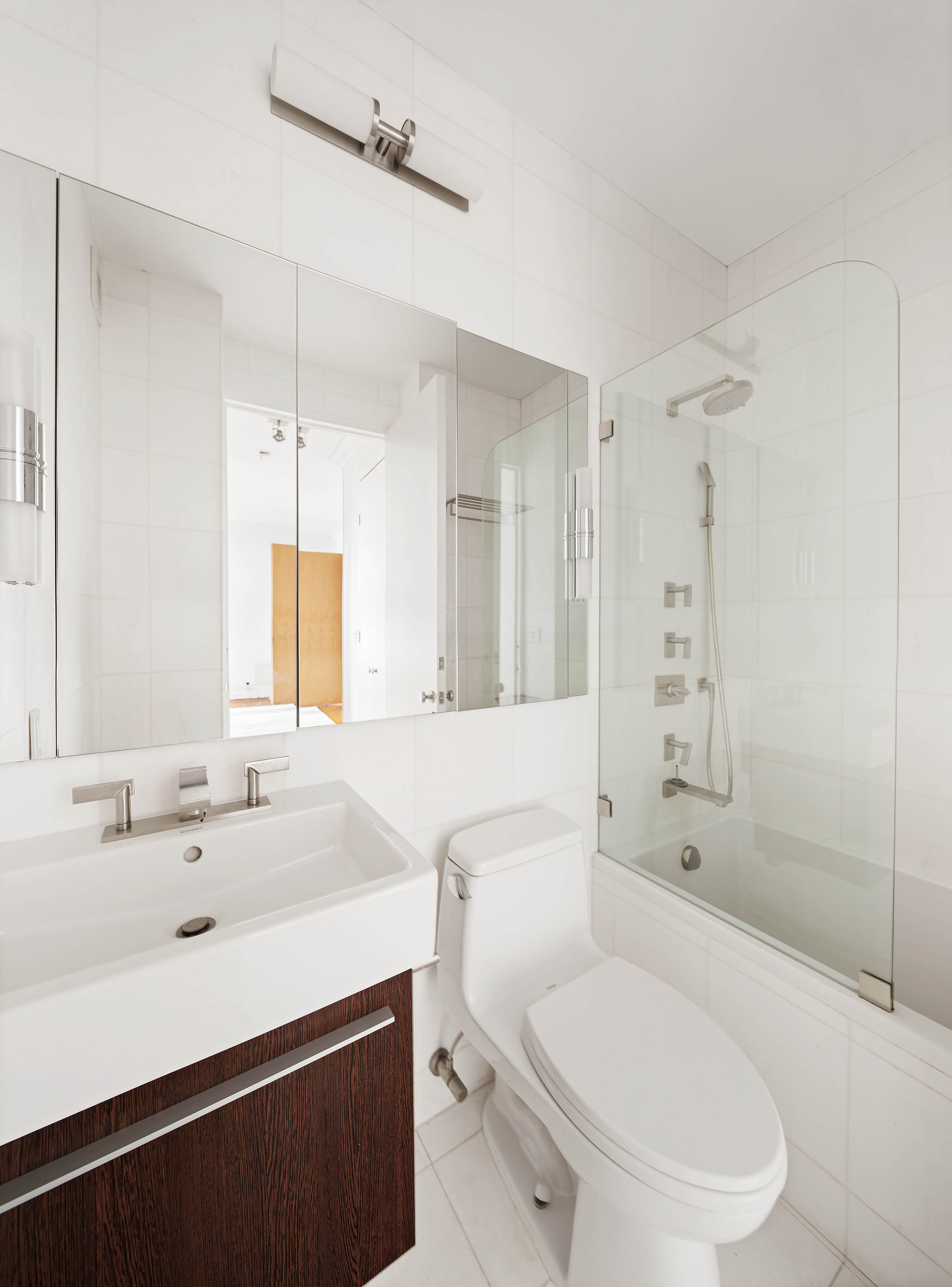 524 East 72nd Street, Unit 28DE Manhattan, NY 10021 - Photo 8 of 14 a bathroom with a sink a toilet a mirror and shower