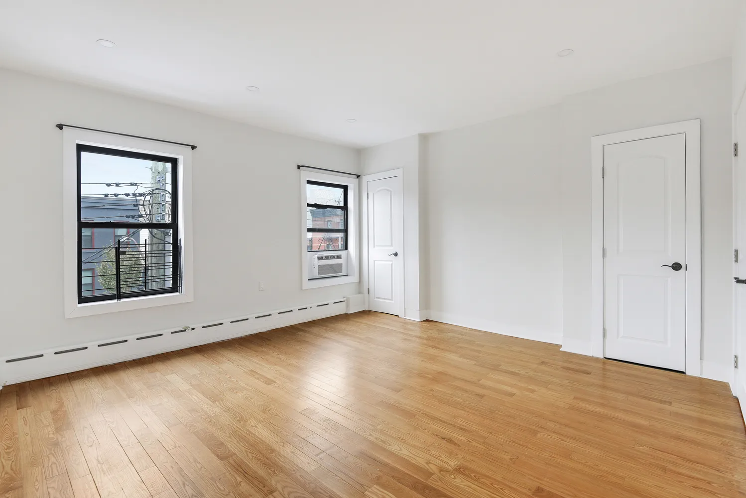 an empty room with wooden floor and windows