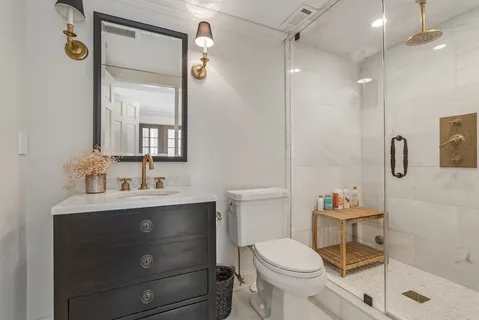 a bathroom with a sink a toilet a mirror and shower