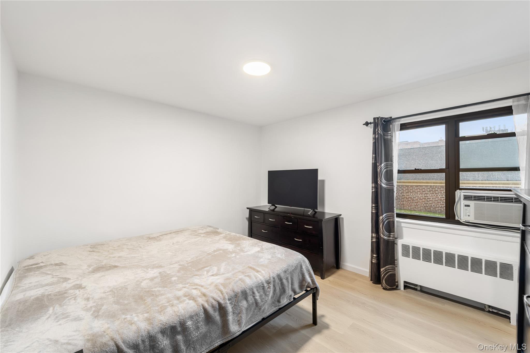 217-14 73rd Avenue, Unit 1 Queens, NY 11364 - Photo 9 of 19 a bedroom with a bed and a flat tv screen on dresser