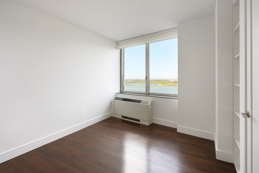 30 West Street, Unit 21AB Manhattan, NY 10004 - Photo 12 of 17 an empty room with wooden floor and windows