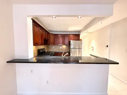 a kitchen with kitchen island granite countertop a sink and a refrigerator