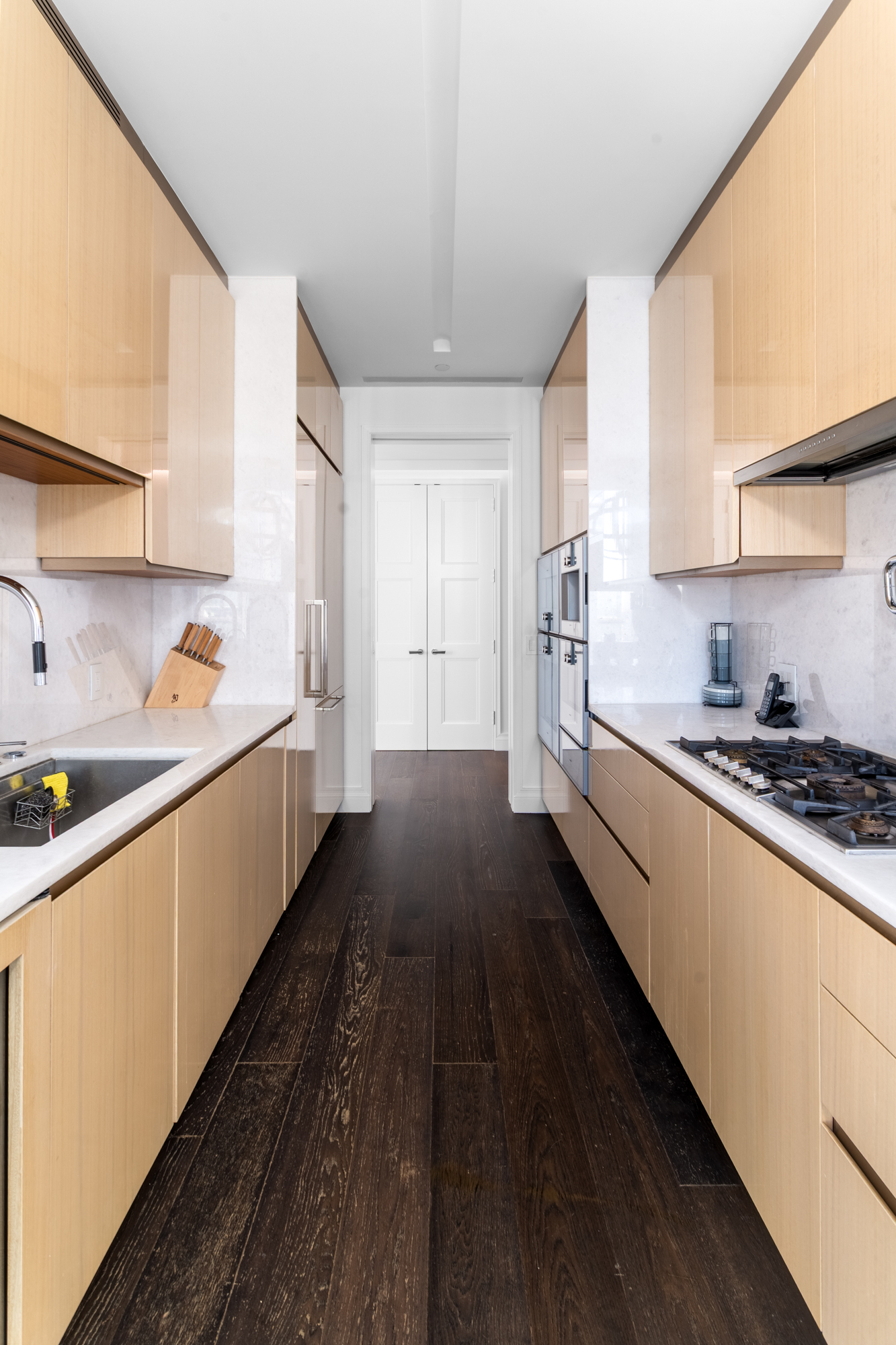 35 Hudson Yards, Unit 5903 Manhattan, NY 10001 - Photo 7 of 15 a kitchen with stainless steel appliances a refrigerator a sink dishwasher a stove and white cabinets with wooden floor
