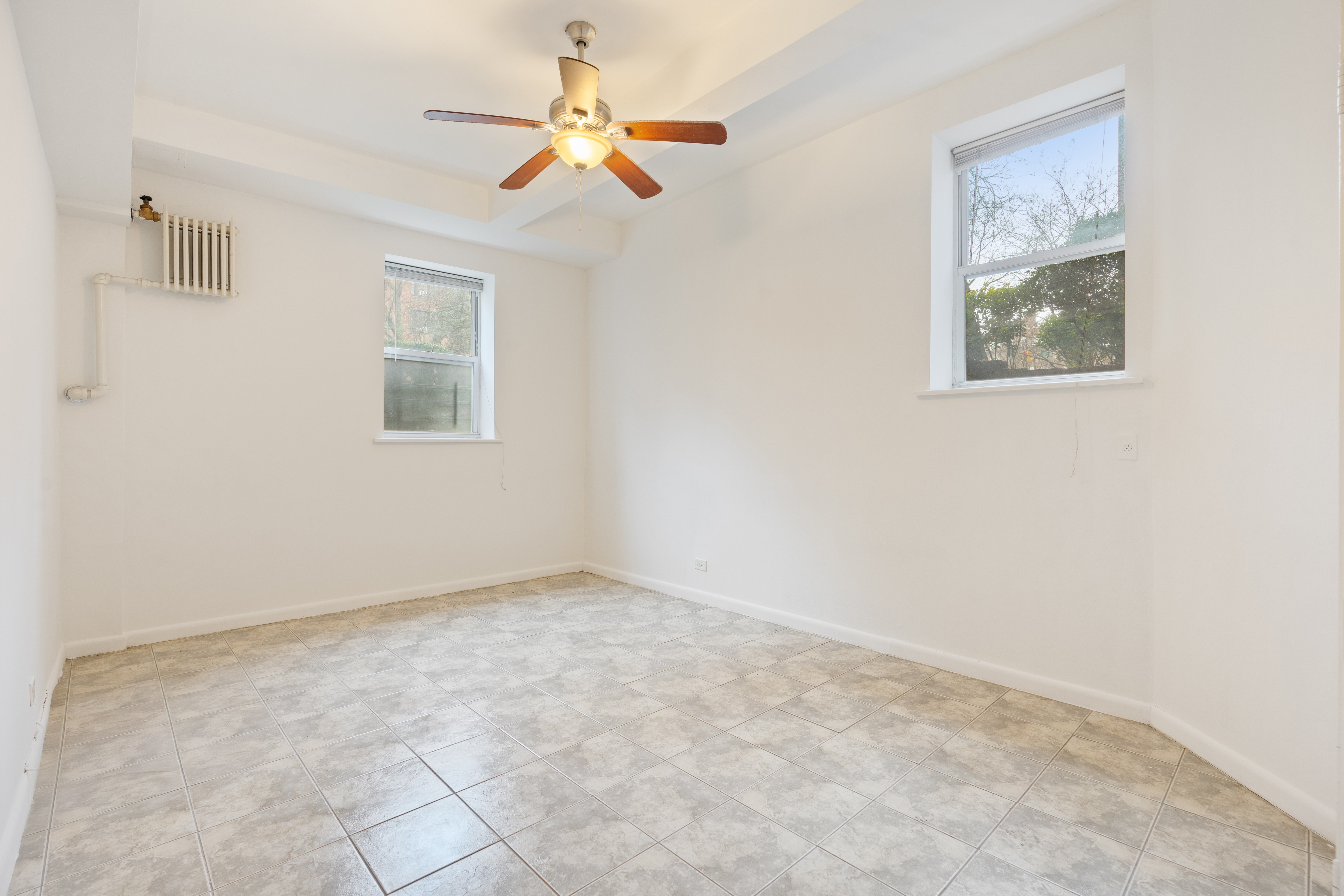68-63 108th Street, Unit 1B Queens, NY 11375 - Photo 3 of 13 an empty room with windows and fan