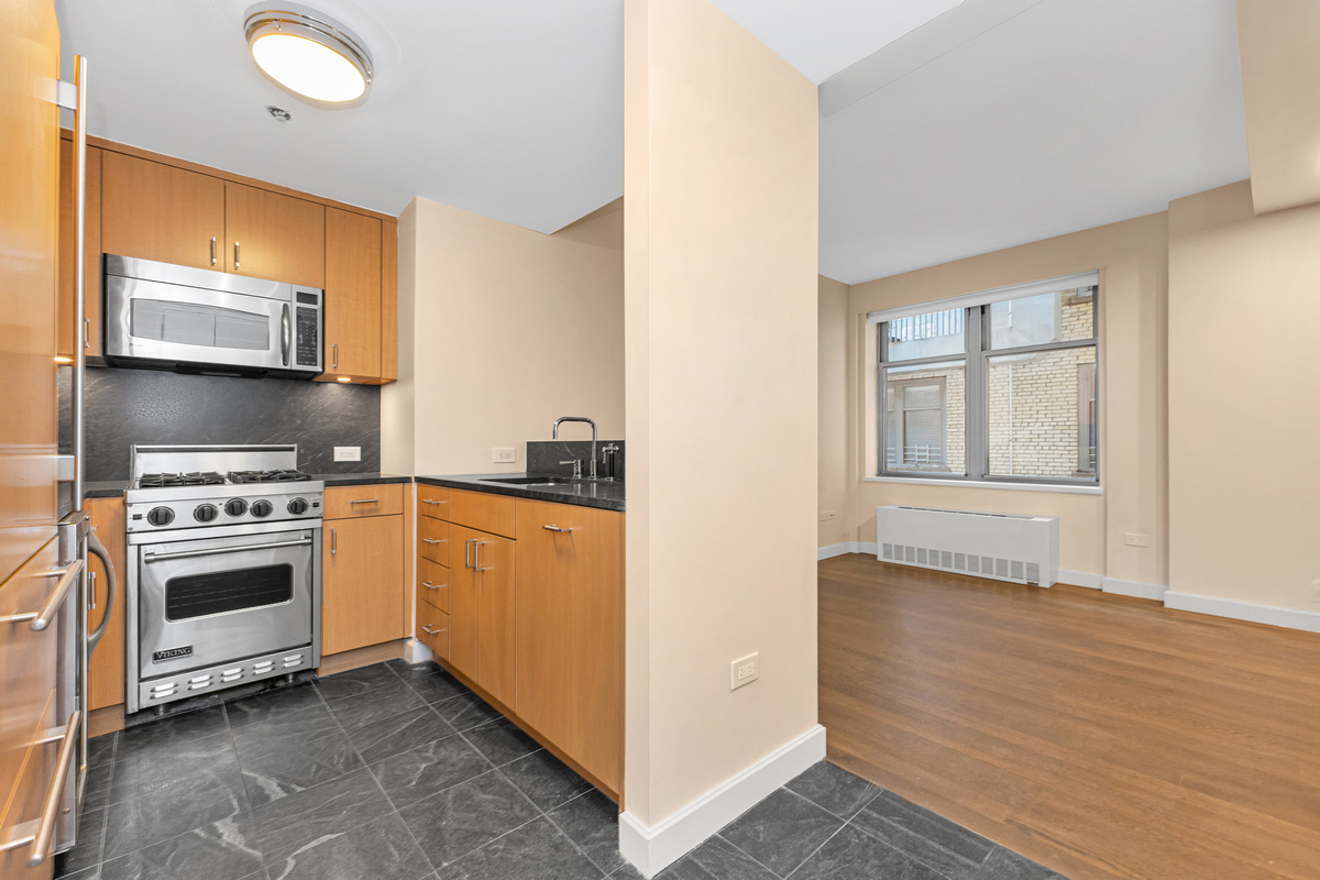 100 West 58th Street, Unit 12A Manhattan, NY 10019 - Photo 4 of 15 a kitchen with granite countertop a stove and a refrigerator