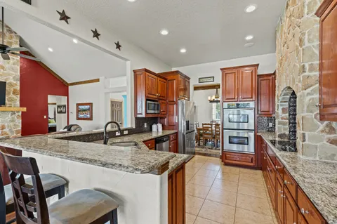 a kitchen with stainless steel appliances granite countertop a refrigerator and a stove top oven