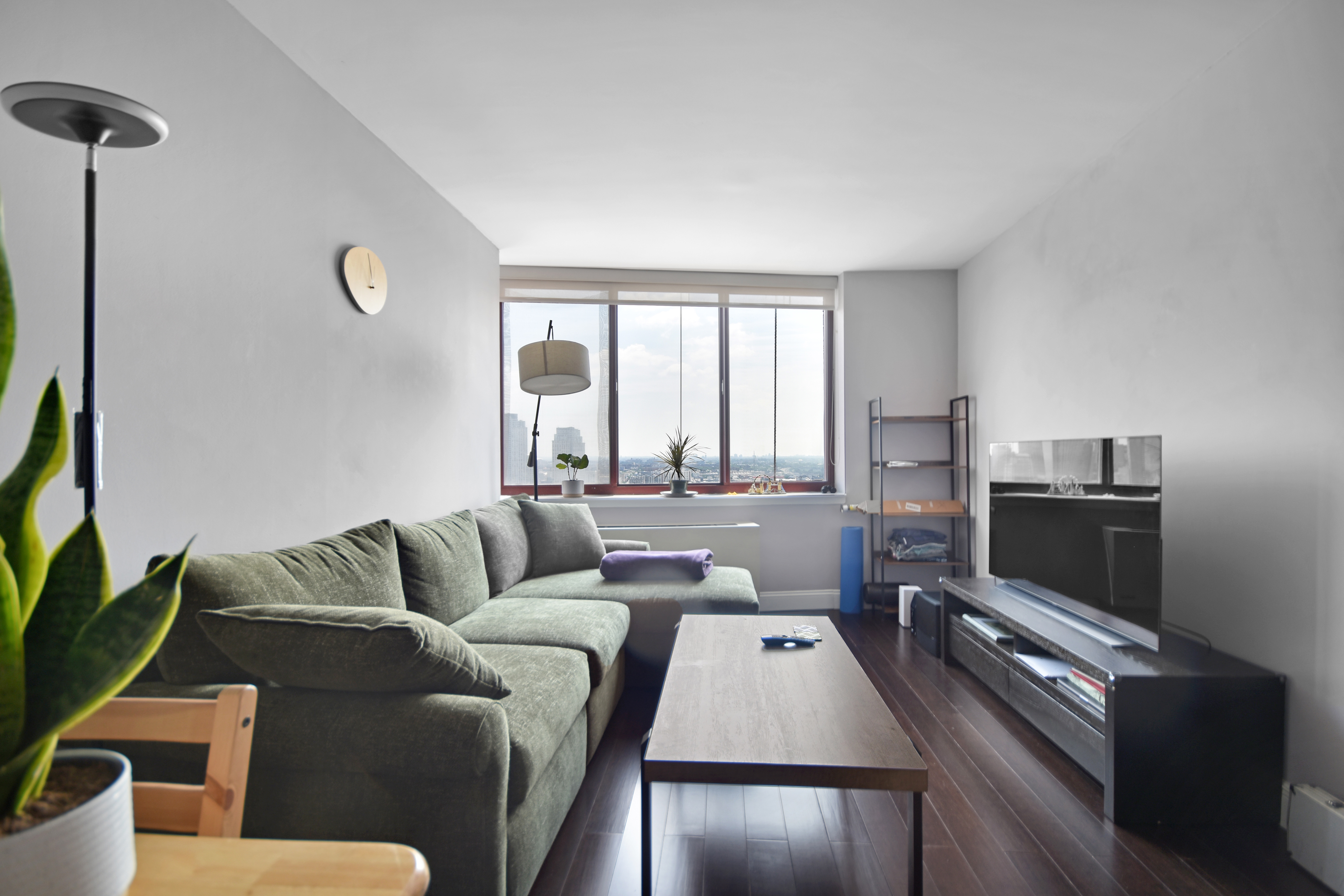 4-74 48th Avenue, Unit 34G Queens, NY 11109 - Photo 1 of 9 a living room with furniture and a flat screen tv