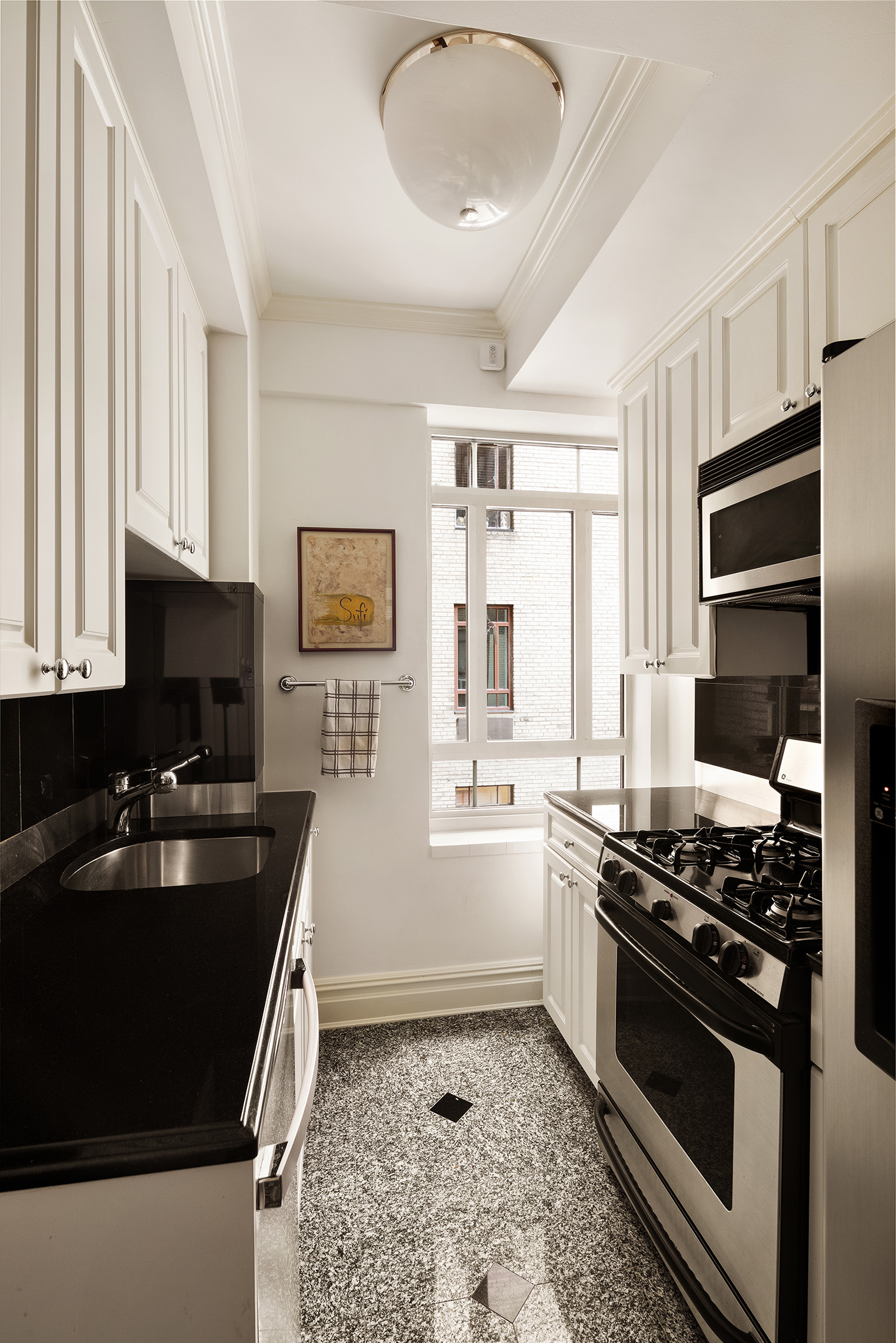 25 Central Park West, Unit 14R Manhattan, NY 10023 - Photo 7 of 22 a kitchen with a stove a sink and a microwave