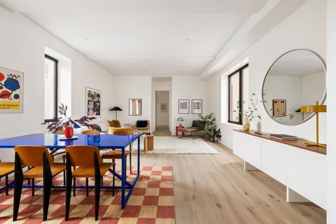 a view of a dining room and livingroom with furniture a rug a potted plant and a painting