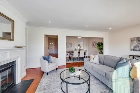 a living room with furniture a fireplace a table and wooden floor