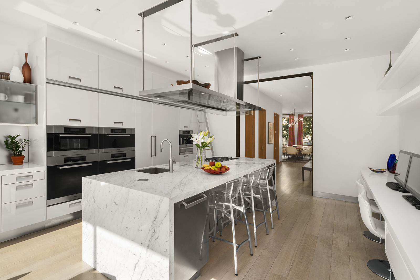 184 East 75th Street Manhattan, NY 10021 - Photo 4 of 20 a kitchen with stainless steel appliances kitchen island granite countertop a table chairs in it and wooden floors