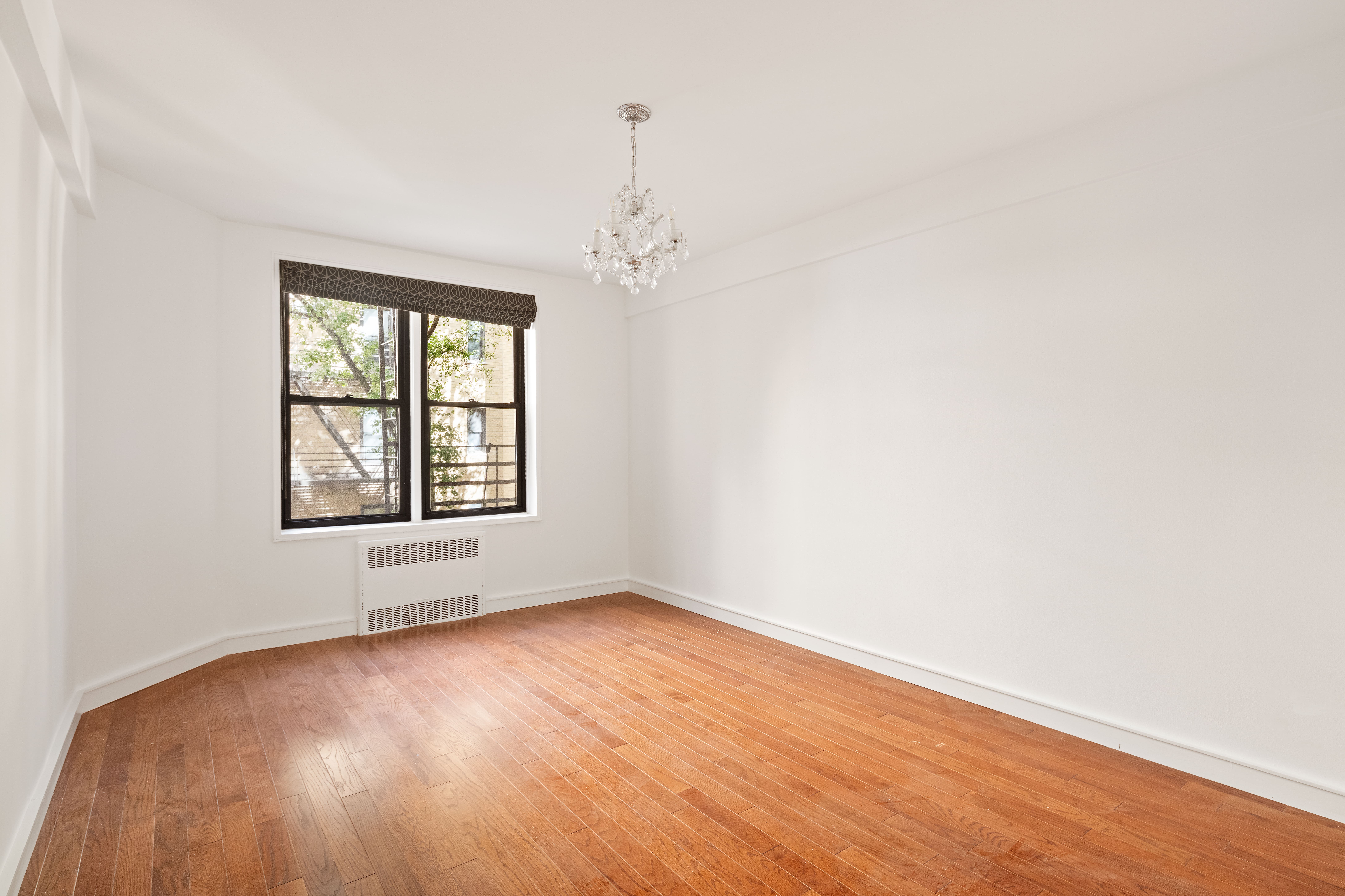 30 East 9th Street, Unit 2II Manhattan, NY 10003 - Photo 8 of 10 an empty room with wooden floor and windows