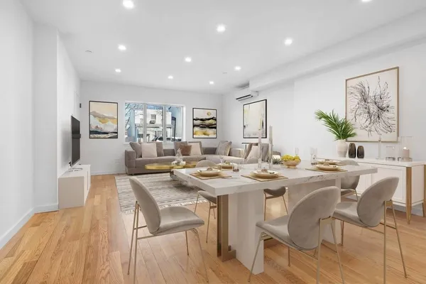 a view of a dining room and livingroom with furniture wooden floor a rug a painting and a chandelier