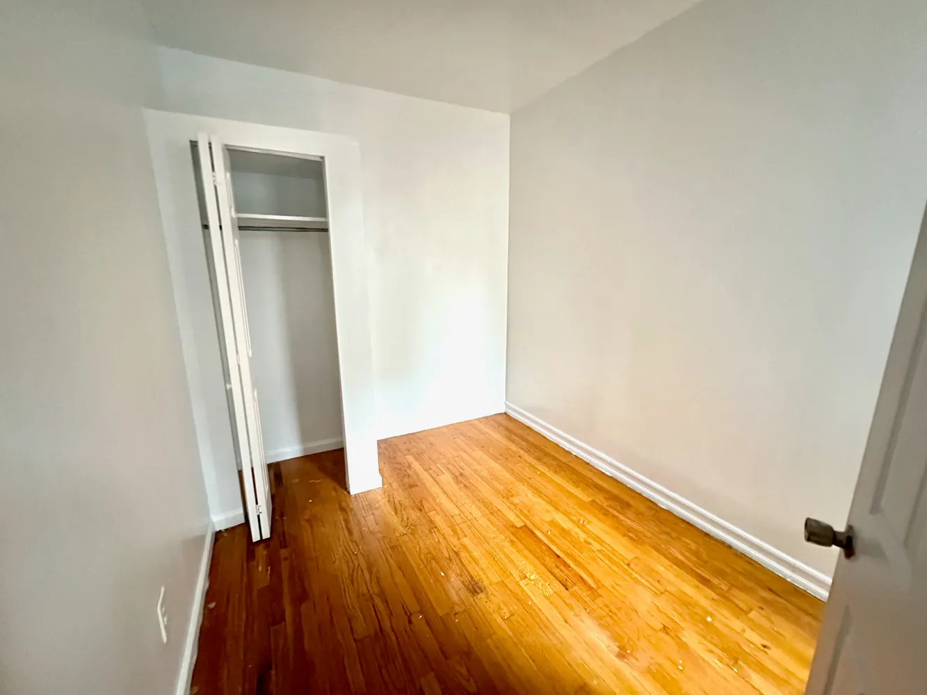 an empty room with wooden floor and closet