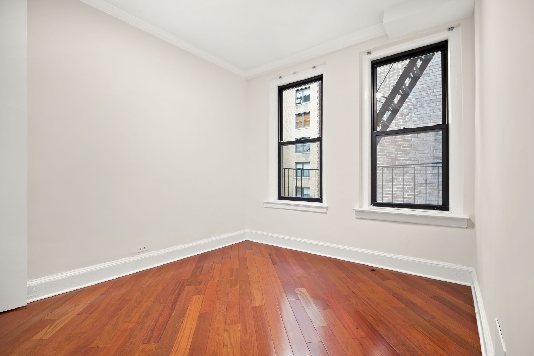 305 West 72nd Street, Unit 7D Manhattan, NY 10023 - Photo 11 of 12 an empty room with wooden floor and windows
