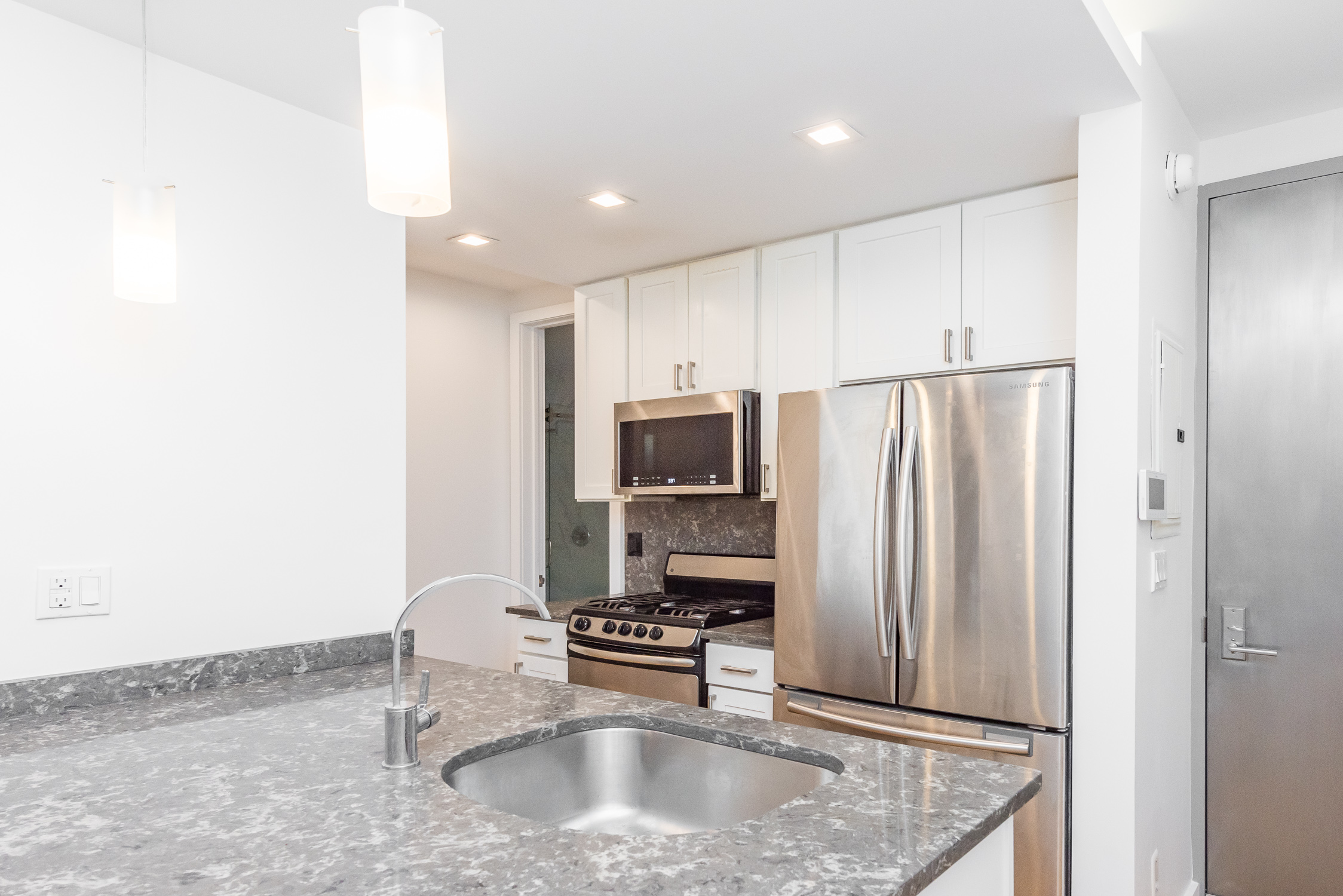 22-11 Steinway Street, Unit 3R Queens, NY 11105 - Photo 2 of 9 a kitchen with stainless steel appliances granite countertop a refrigerator a stove and a sink with wooden cabinets