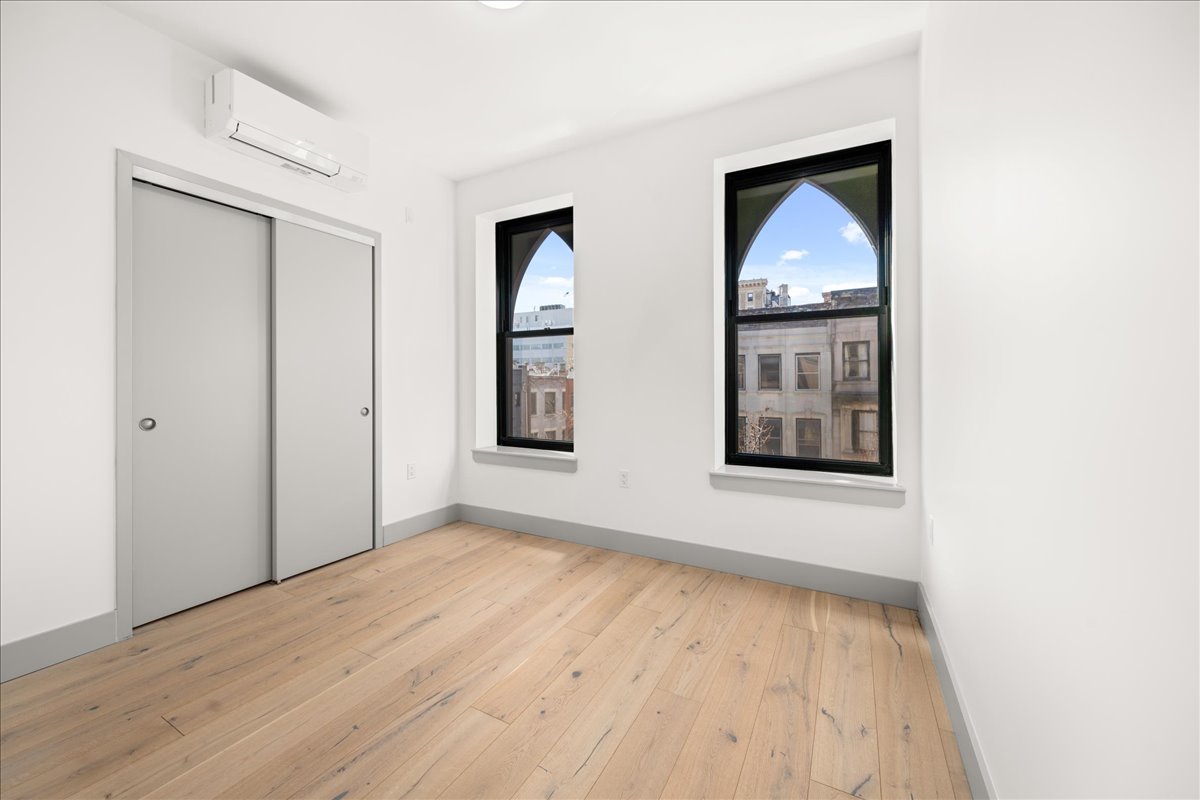 463 West 142nd Street, Unit 4B Manhattan, NY 10031 - Photo 5 of 10 an empty room with wooden floor and windows