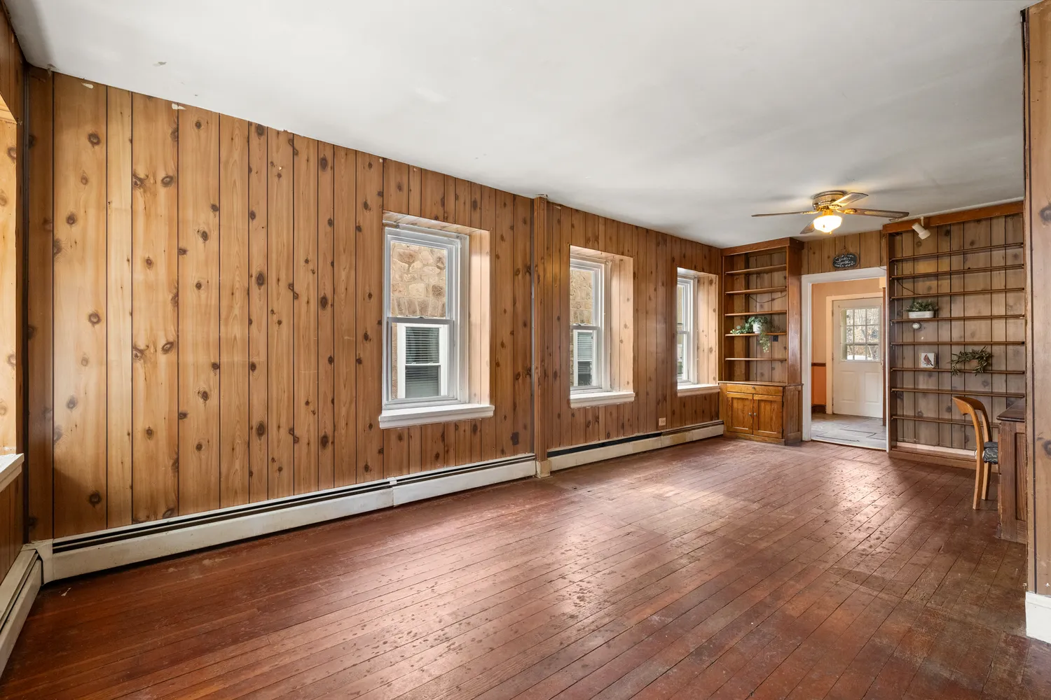 an empty room with wooden floor and windows