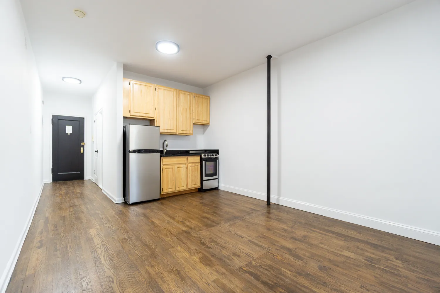 a view of kitchen with refrigerator cabinets and wooden floor