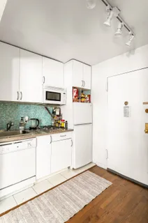a kitchen with granite countertop a refrigerator a stove a sink and white cabinets