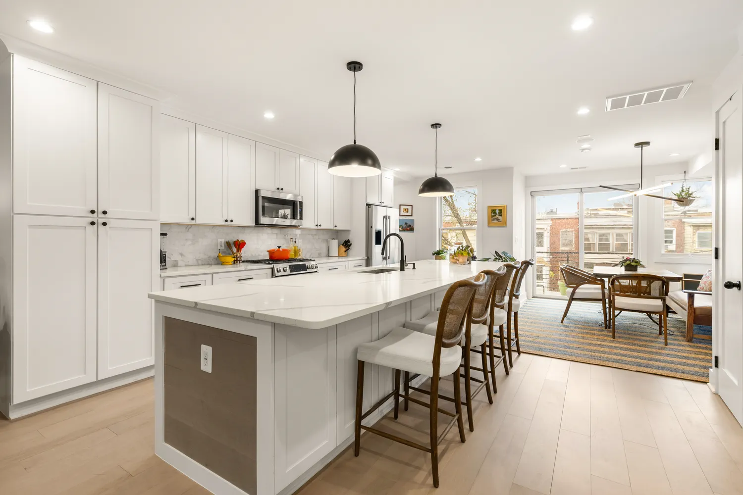 a kitchen with stainless steel appliances kitchen island granite countertop a table chairs and a refrigerator