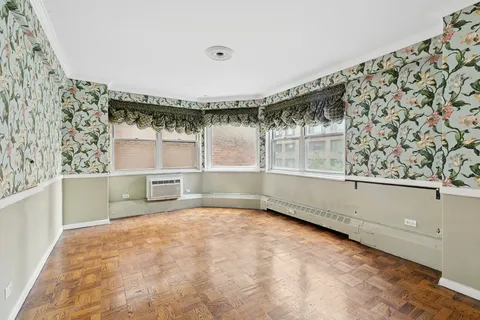 a view of a big room with wooden floor and windows