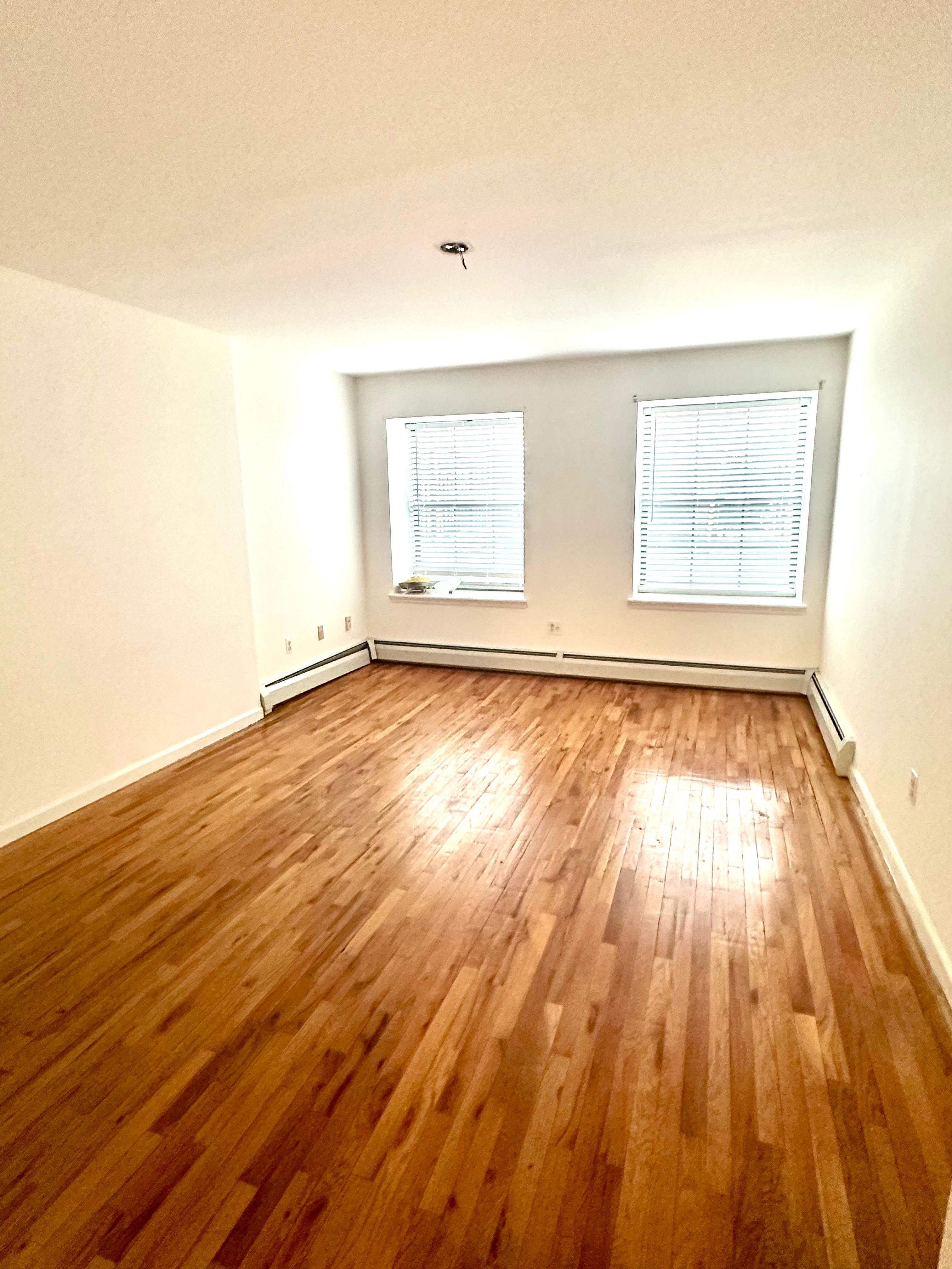 710 St Nicholas Avenue, Unit 1 Manhattan, NY 10032 - Photo 9 of 15 an empty room with wooden floor and windows