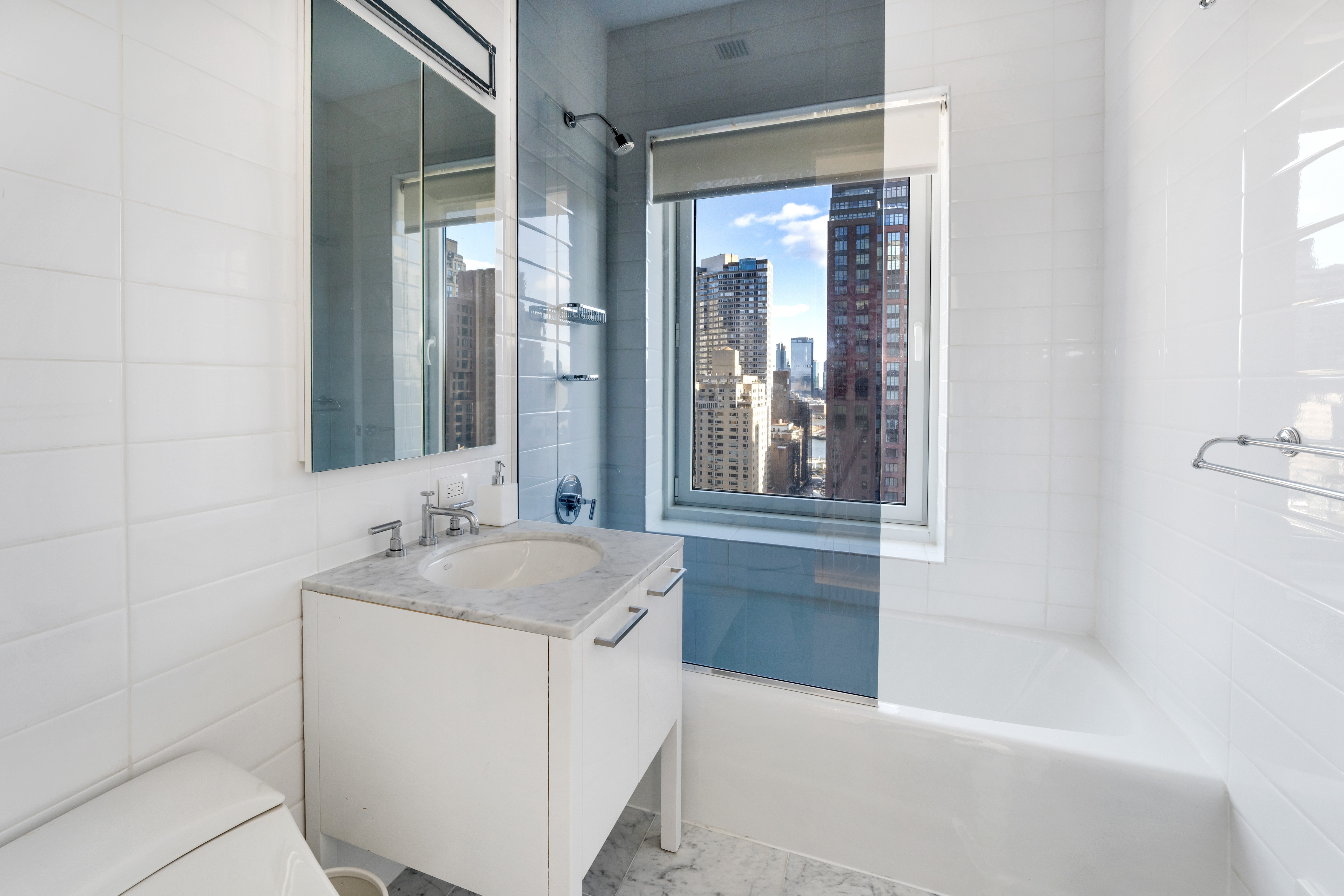 310 East 53rd Street, Unit 18A Manhattan, NY 10022 - Photo 16 of 19 a bathroom with a granite countertop tub sink and mirror
