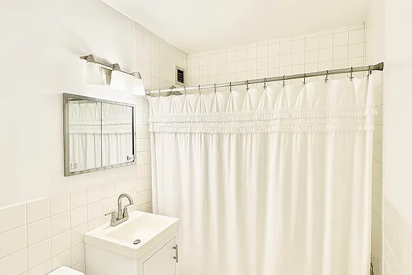 61 Lexington Avenue, Unit 4H Manhattan, NY 10010 - Photo 5 of 6 a bathroom with a sink a mirror and a shower curtain