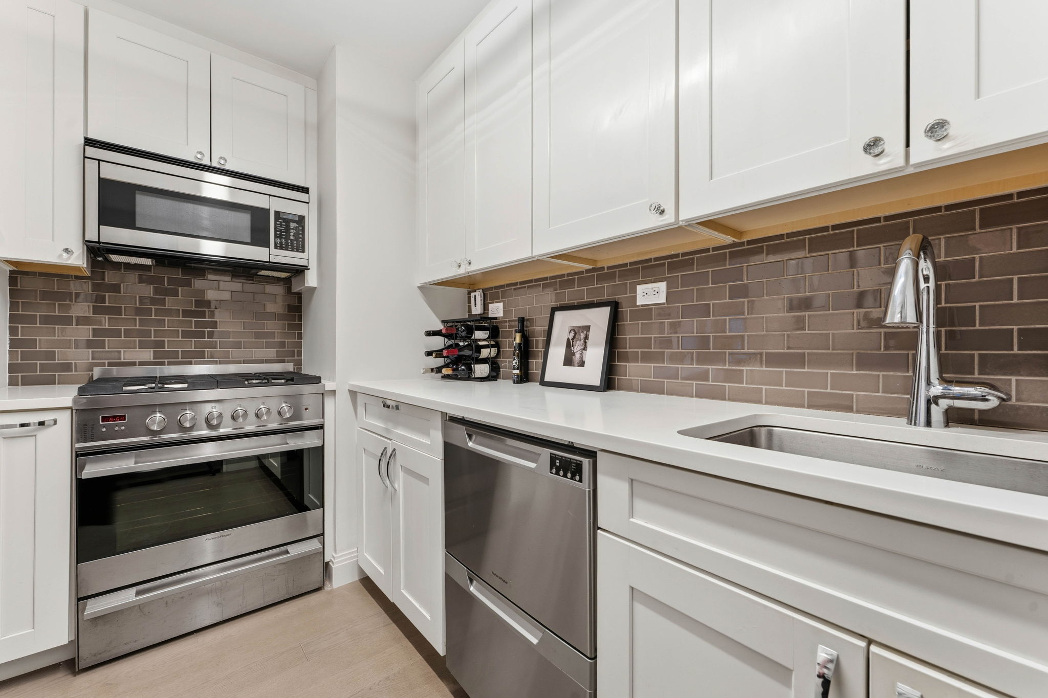 245 East 87th Street, Unit 17C Manhattan, NY 10128 - Photo 5 of 11 a kitchen with white cabinets and stainless steel appliances
