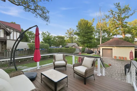 a view of a patio with couches and a table and chairs with wooden floor and fence