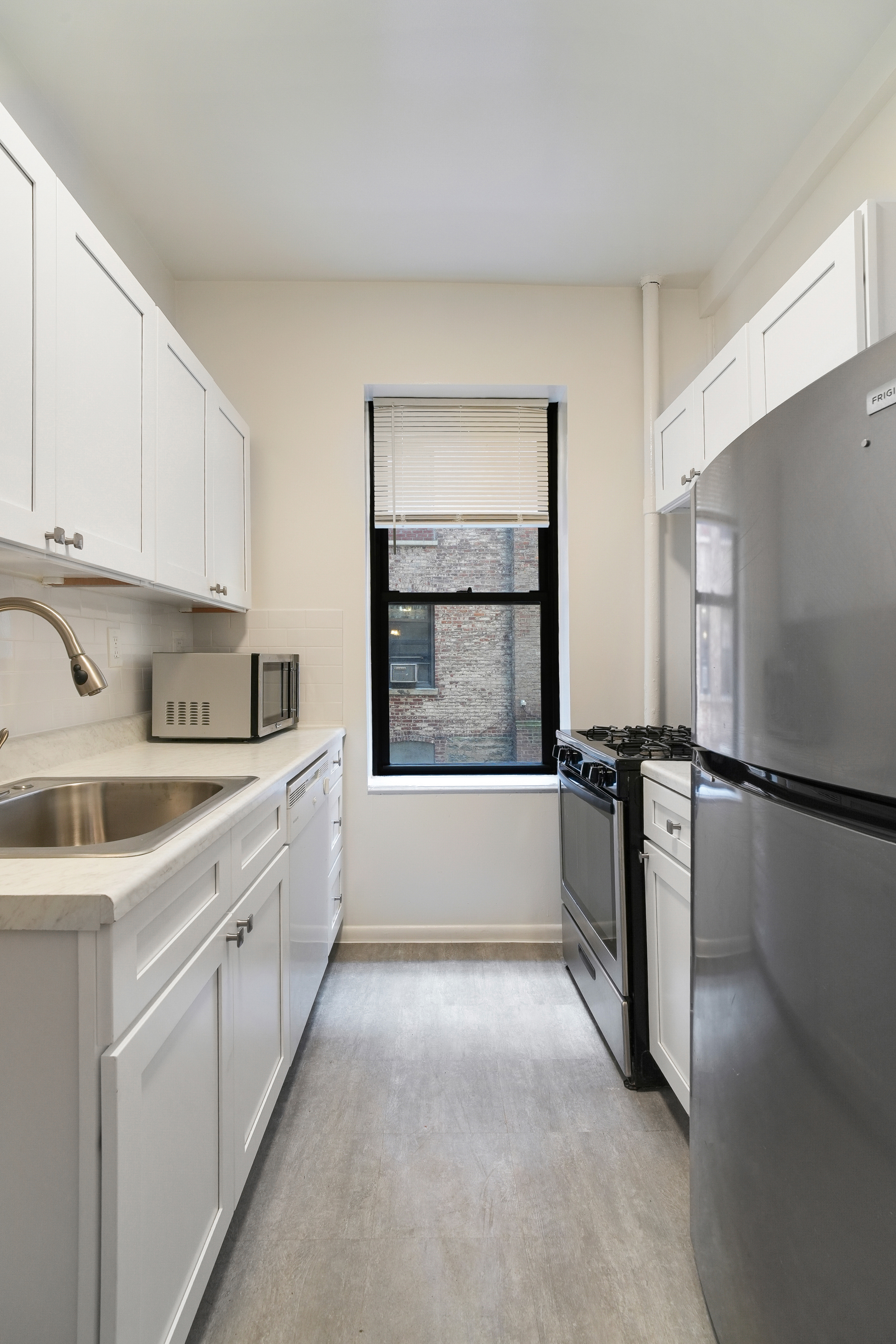 507 West 111th Street, Unit 3 Manhattan, NY 10025 - Photo 3 of 11 a kitchen with a refrigerator a stove and white cabinets