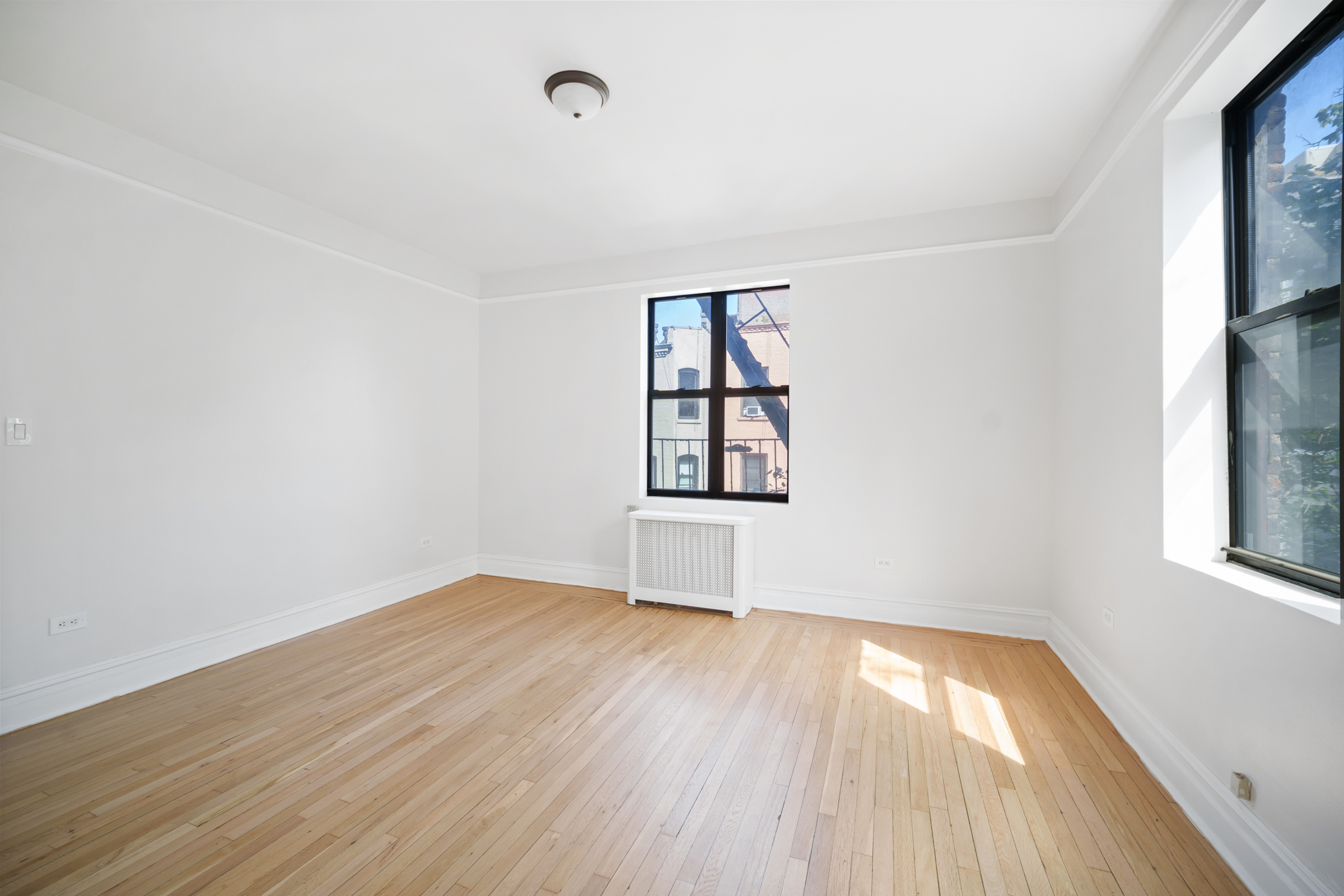 690 Riverside Drive, Unit 3F Manhattan, NY 10031 - Photo 5 of 19 an empty room with wooden floor and windows