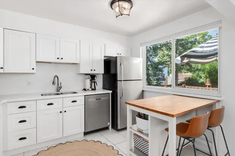 a kitchen with stainless steel appliances granite countertop a stove a refrigerator a sink a stove and white cabinets with wooden floor