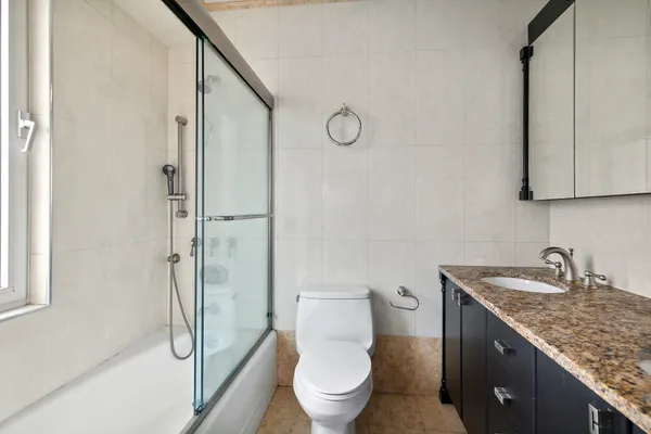 a bathroom with a granite countertop sink toilet and shower