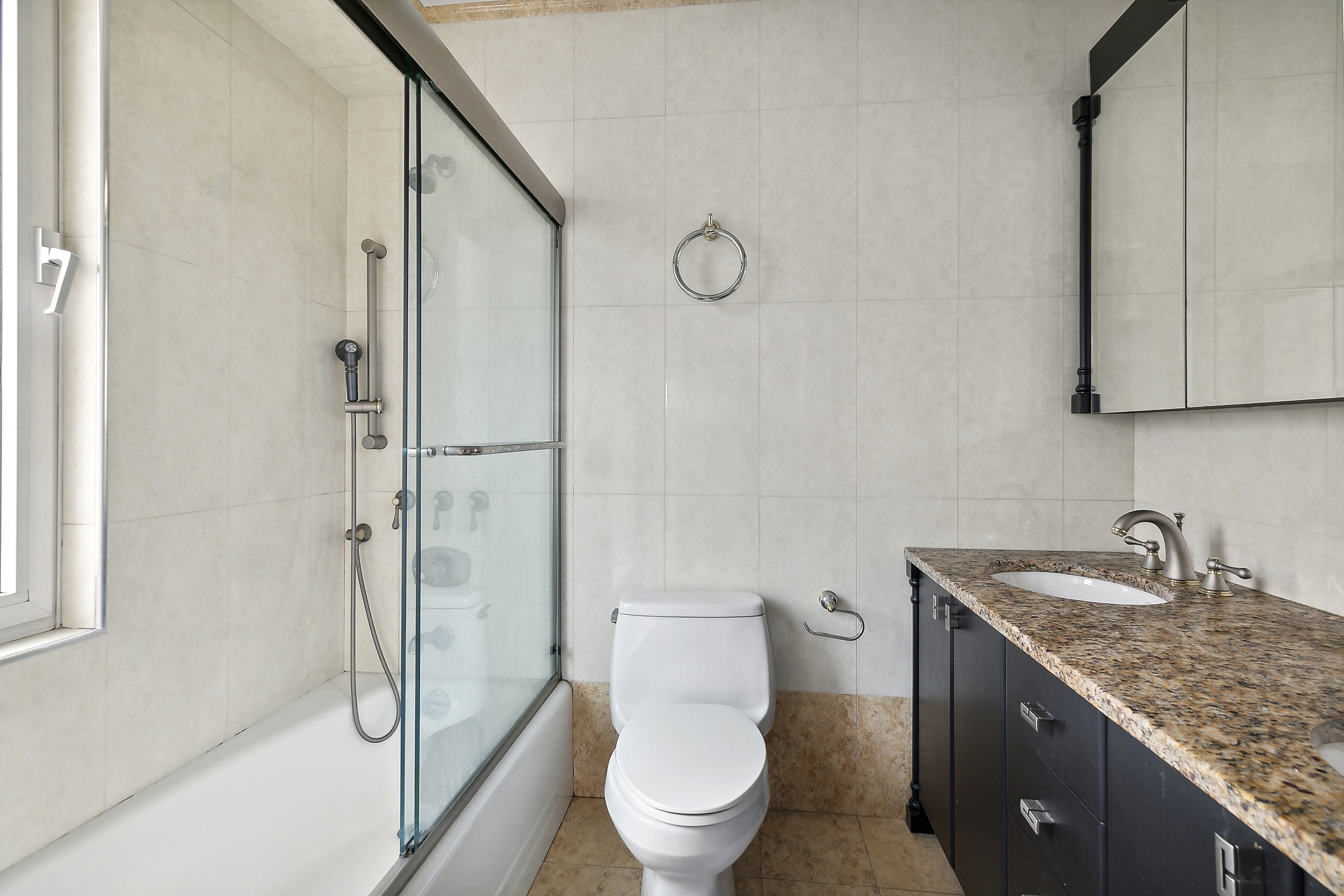 303 East 57th Street, Unit 11L Manhattan, NY 10022 - Photo 5 of 11 a bathroom with a granite countertop sink toilet and shower