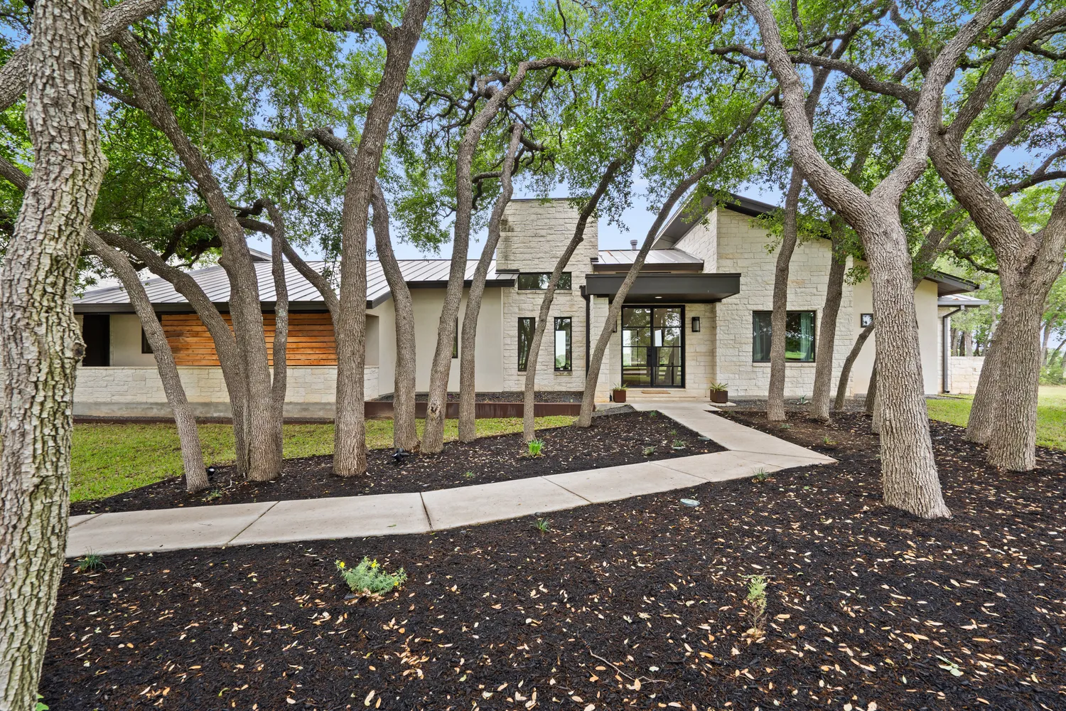 a view of a white house next to a road and large trees