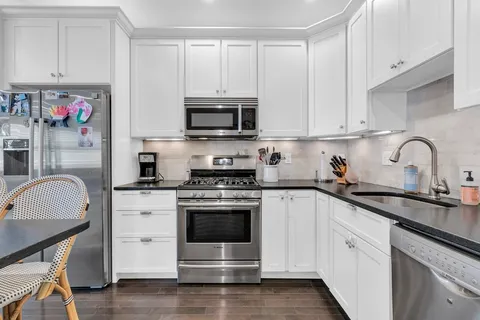 a kitchen with stainless steel appliances granite countertop a stove a sink and white cabinets