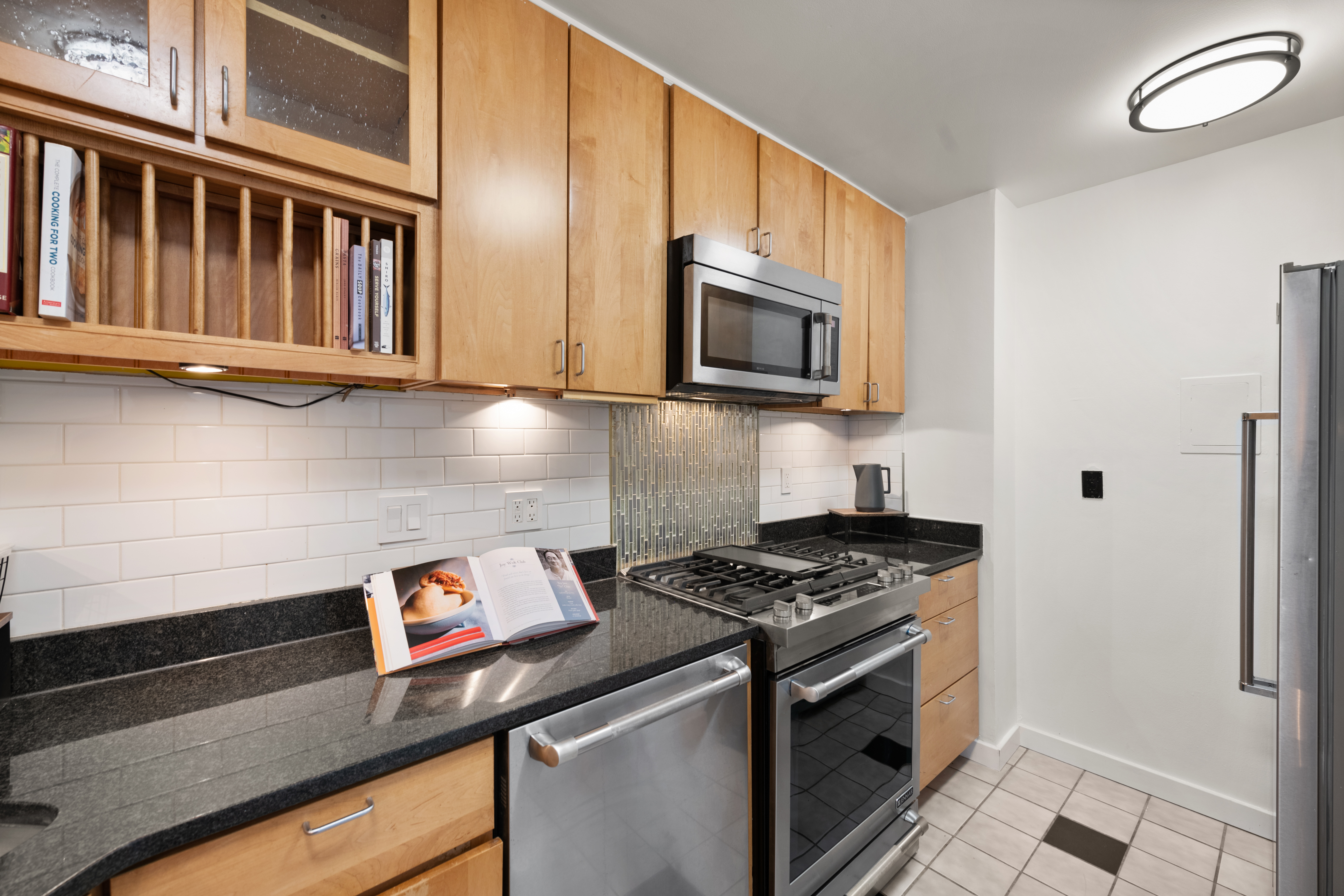 490 M Street Southwest, Unit W802 Washington, DC 20024 - Photo 13 of 24 a kitchen with stainless steel appliances granite countertop a stove a microwave and a refrigerator